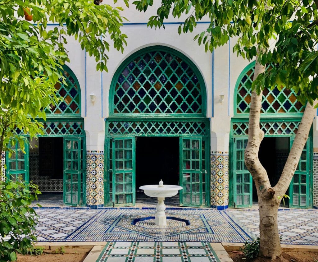 Courtyard of Bahia Palace in Marrakech with green carved arches and a fountain